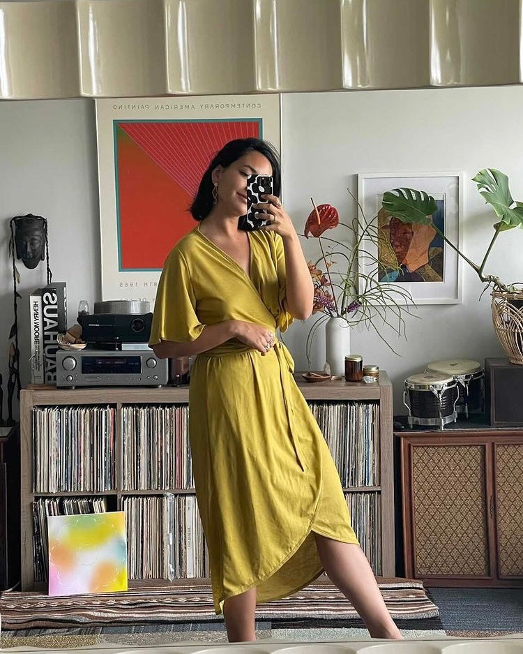 Mirror selfie shot of a girl wearing mustard dress in her lounge.