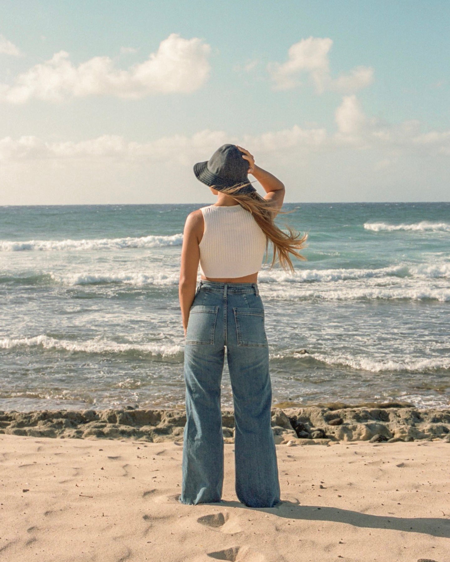 Back shot of girl wearing unisex denim bucket hat, at the beach.